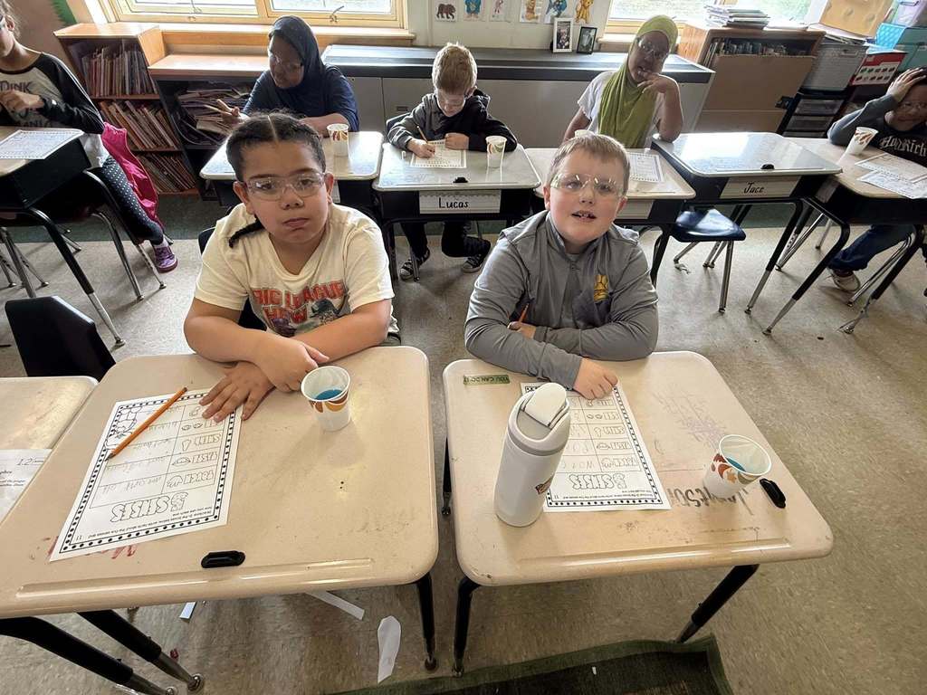 Two students posing at their desks in class. 