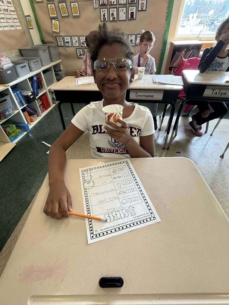 A young girl holding a cup in one hand and posing. 