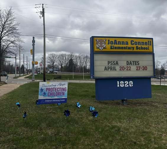 The JoAnna Connell Elementary School sign and a smaller yard sign next to it that says "protecting children". 