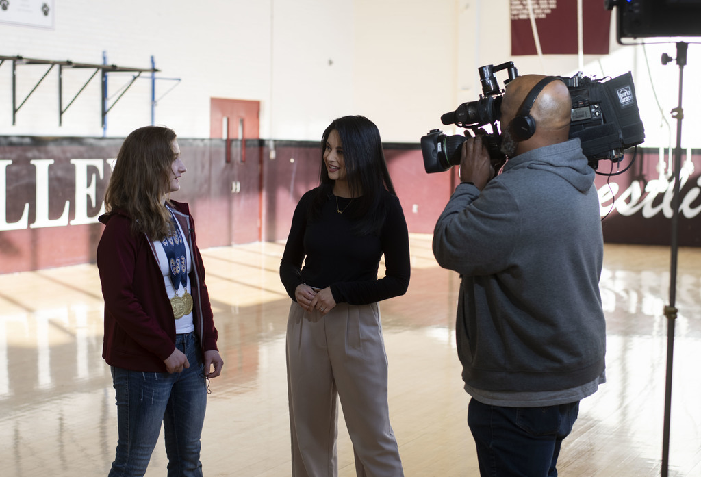 Neve being interviewed by Jen Carabeao from CBS3 in the GVHS wrestling gym.  A cameraman is videoing the interview.