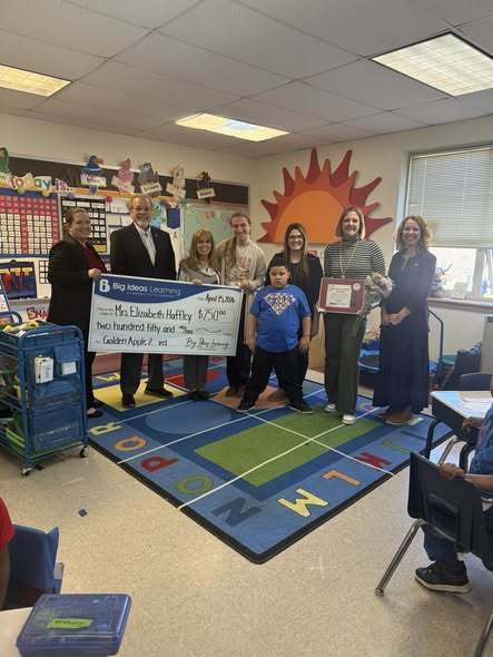 People posing with the Golden Apple Recipient and holding a big check. 