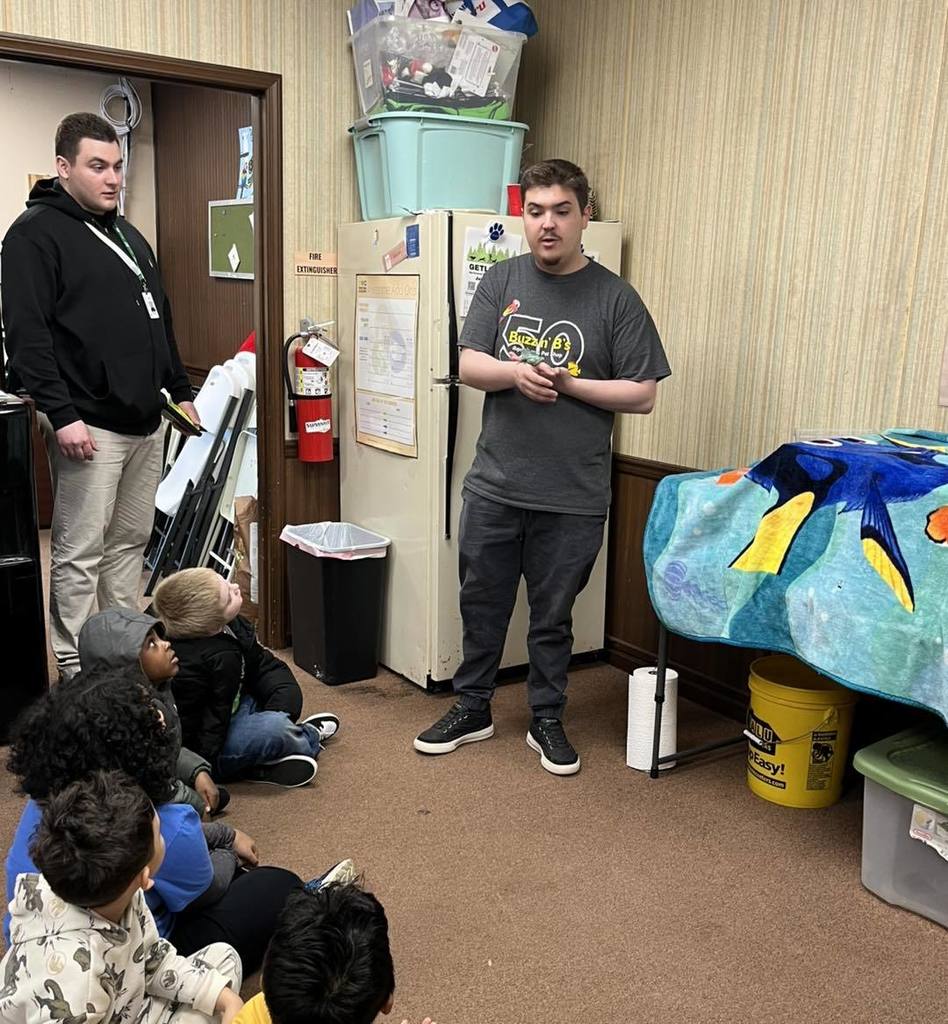 A man holding an animal as he talks to students.