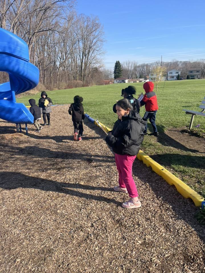 A student in a playground walking while holding a clipboard. 