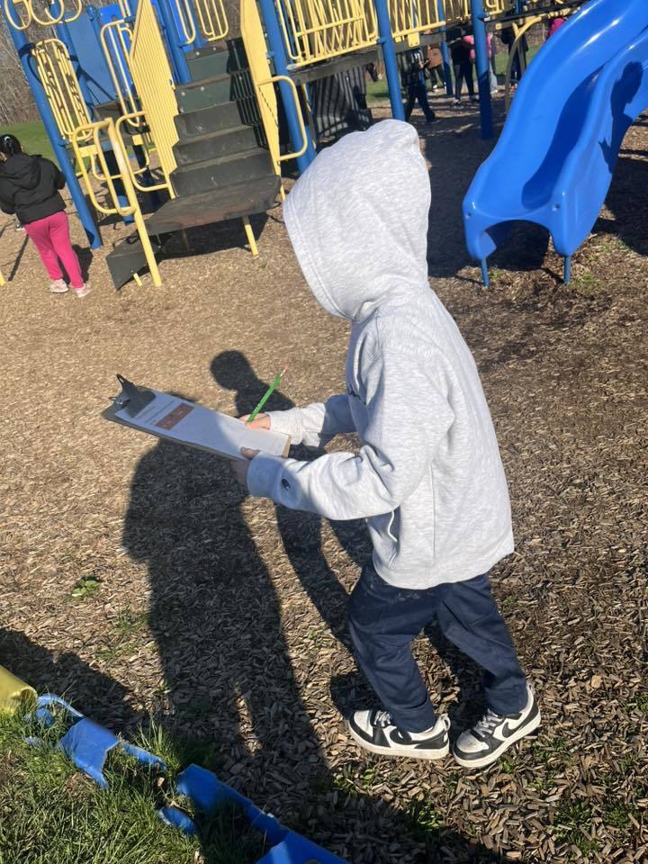 A student in a playground walking while holding a clipboard. 