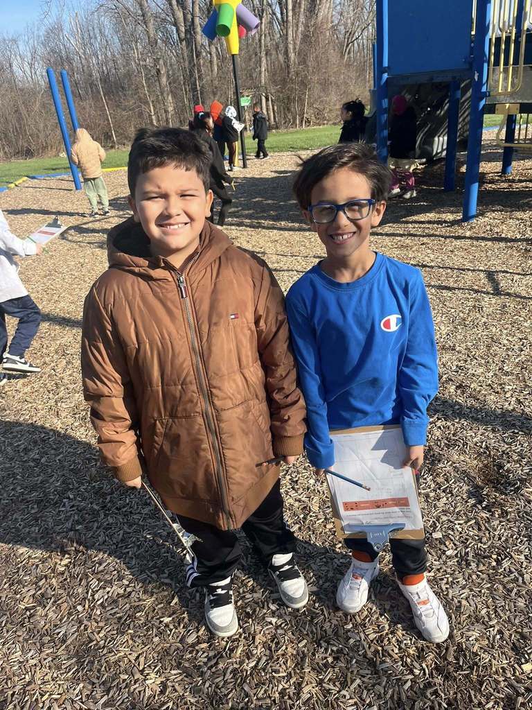 Two students posing while holding their clipboards. 