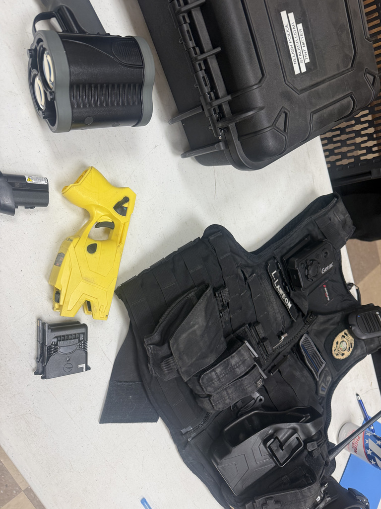 law enforcement protective vest, stun gun and other supplies used by law enforcement on display on a table at the job fair