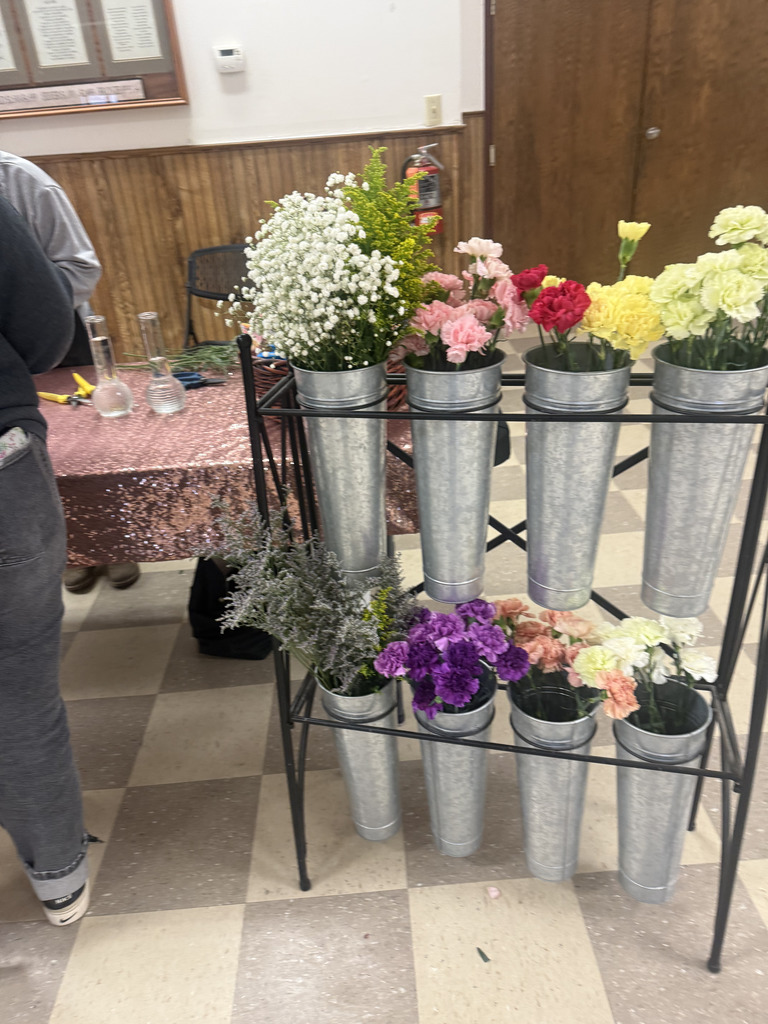 a variety of long stem flowers  in different silver colored pots to be used by students to make their own floral arrangements