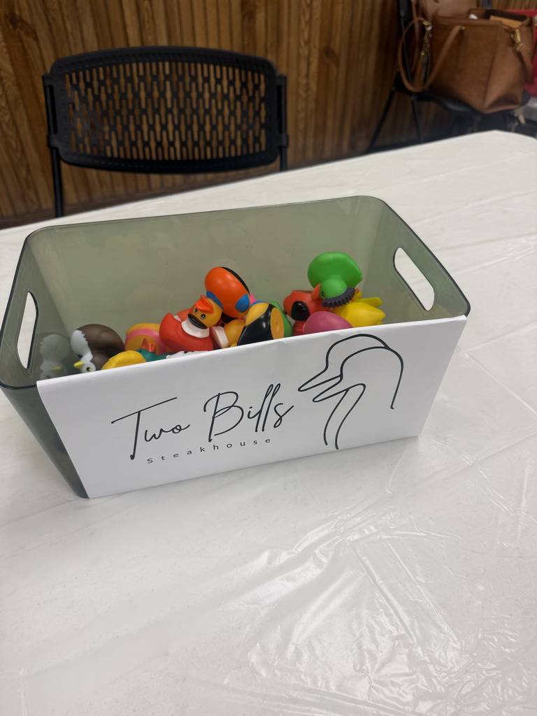 a rectangle shaped container with assorted rubber duckies inside it and on the front is a Two Bills Steakhouse sign