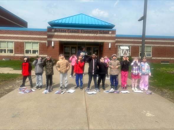 Students looking up at the sky in front of JoAnna Connell School. 