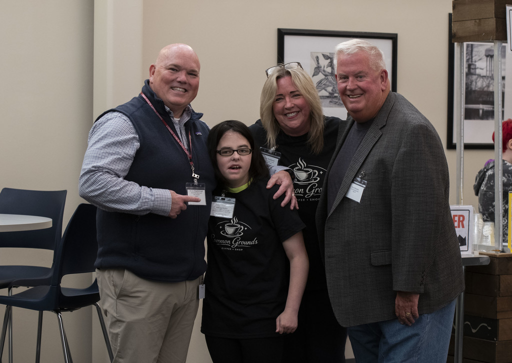 GVHS Assistant principal, Dr. Joe Kingsborough poses with and  points to Ashley, Common Grounds helper alongside two adults.