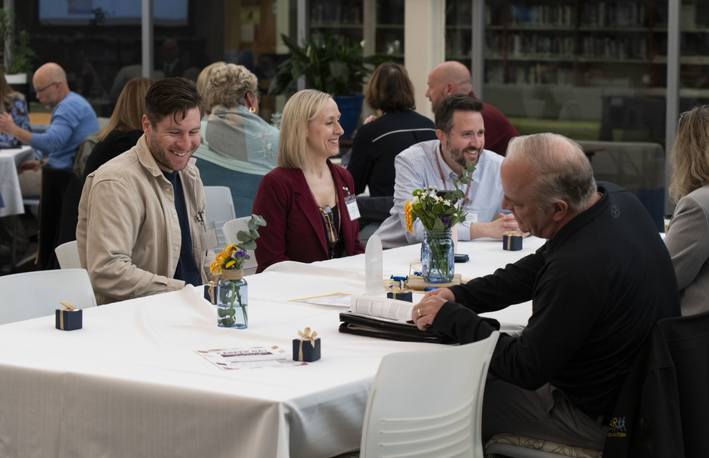 People smiling and talking, sitting at a table.