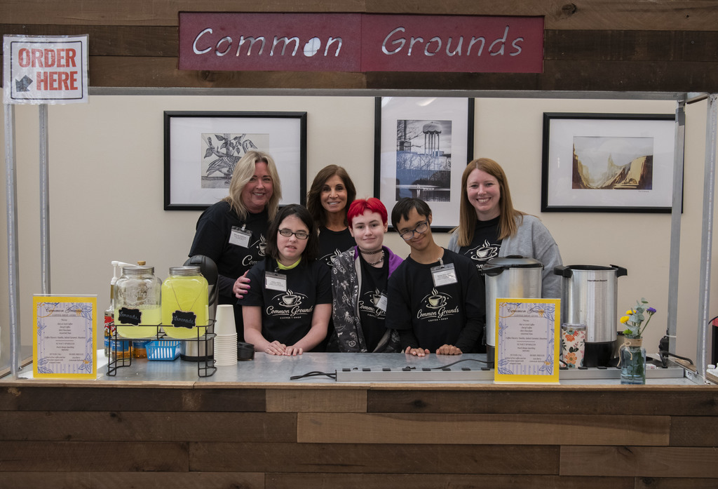 Students and teachers posing in front of coffee cart called "Common Grounds."