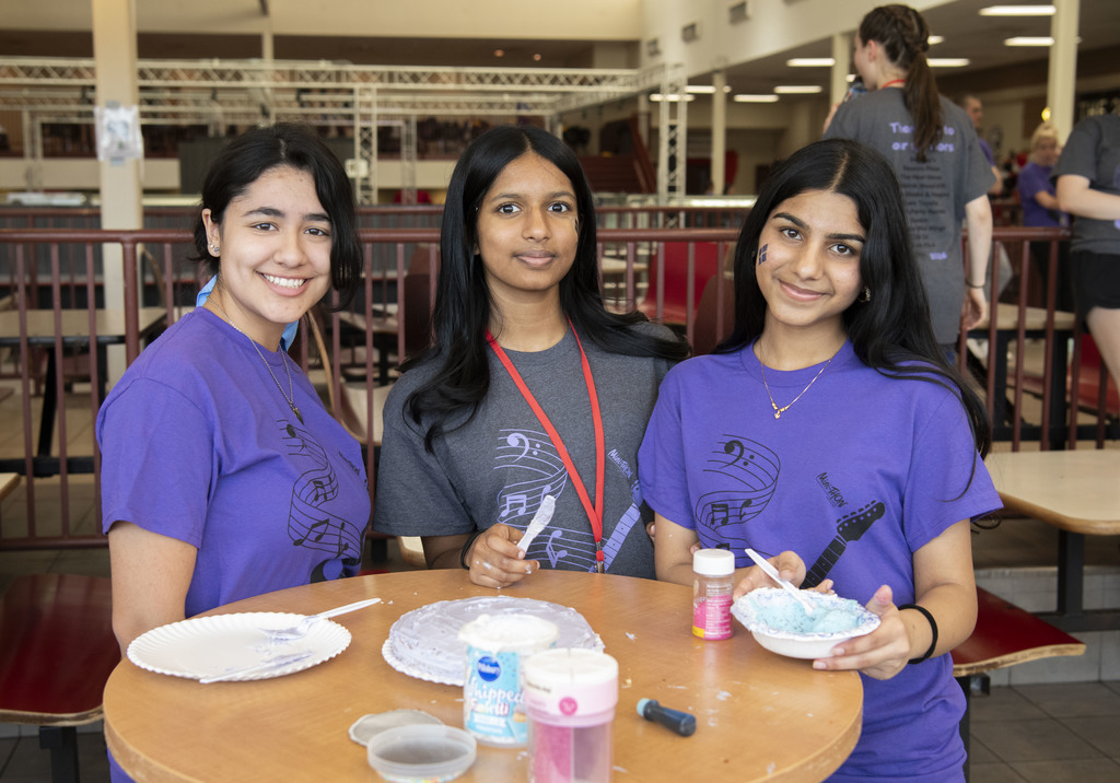 three students posing by the cake they just made