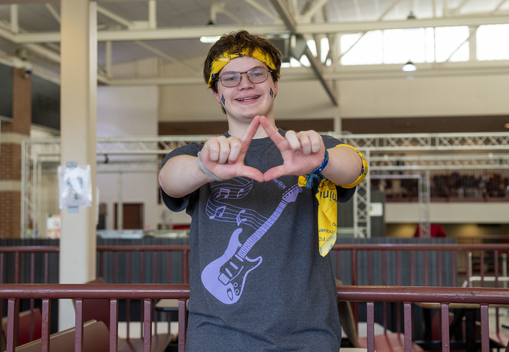 A student making a 4 diamonds MiniThon symbol with his hands