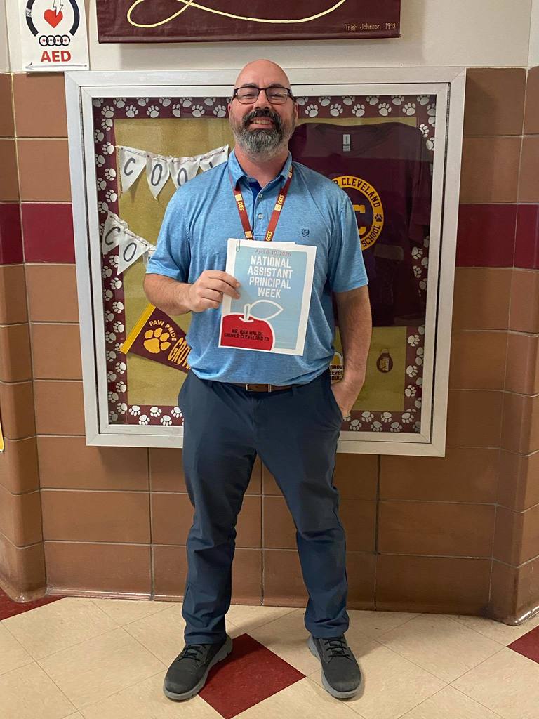 The assistant Principal, Dan Walsh, posing and holding a paper that says "National Assistant Principal Week".