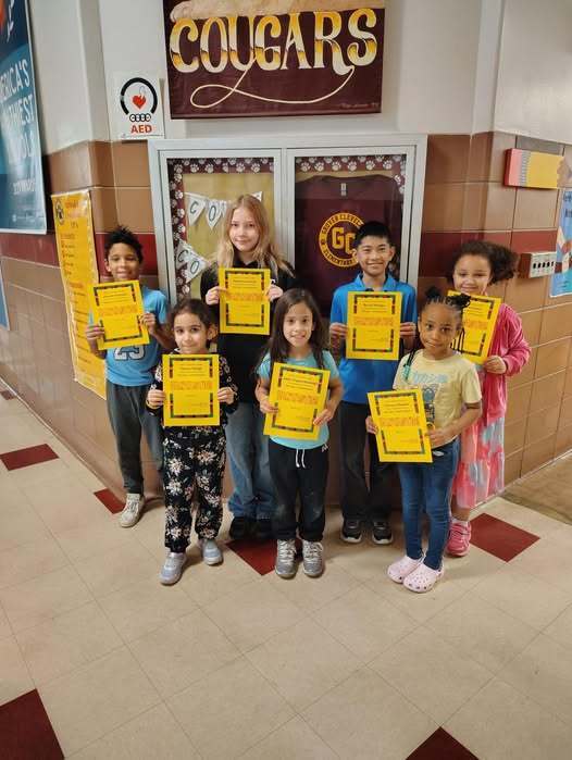 Students holding up yellow awards for Cook Cougar's.