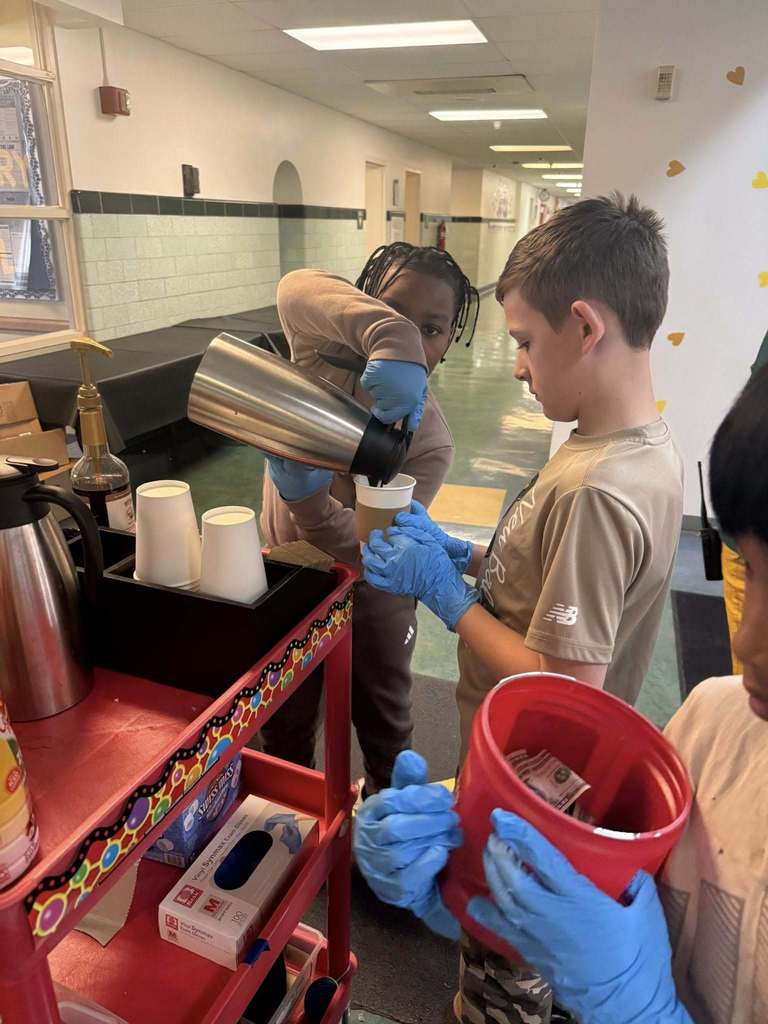 Two students pouring coffee into a cup. 