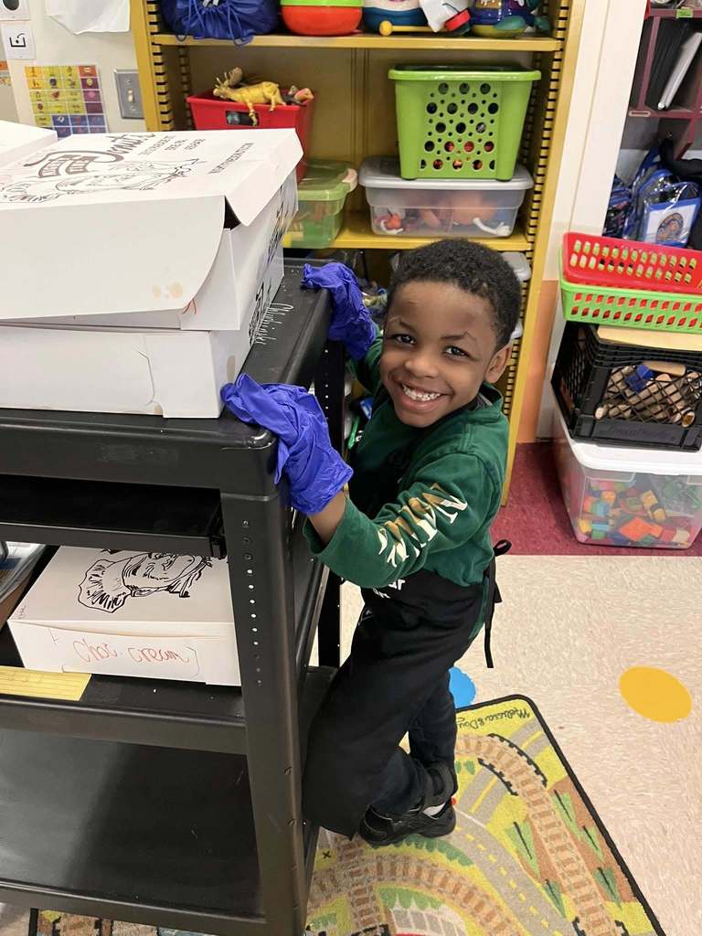 A kid smiling with blue gloves on. 