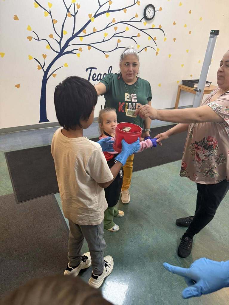 Kids holding a container for staff to put money into after they receive their donut and coffee.