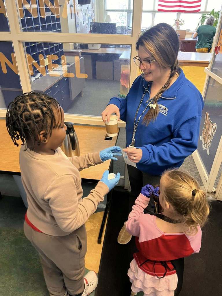 Students giving a teacher a cup of coffee.