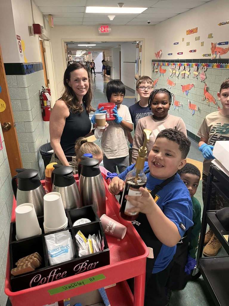Students and teacher posing in front of the coffee on a cart.