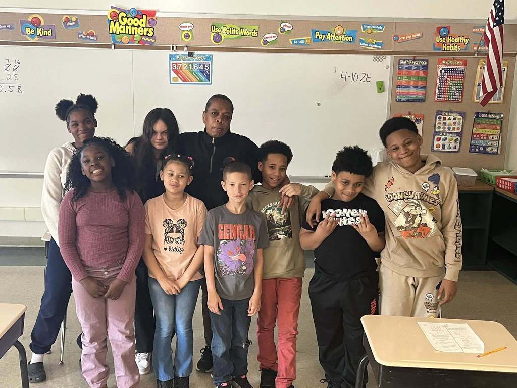 Students and adults posing in a classroom. 