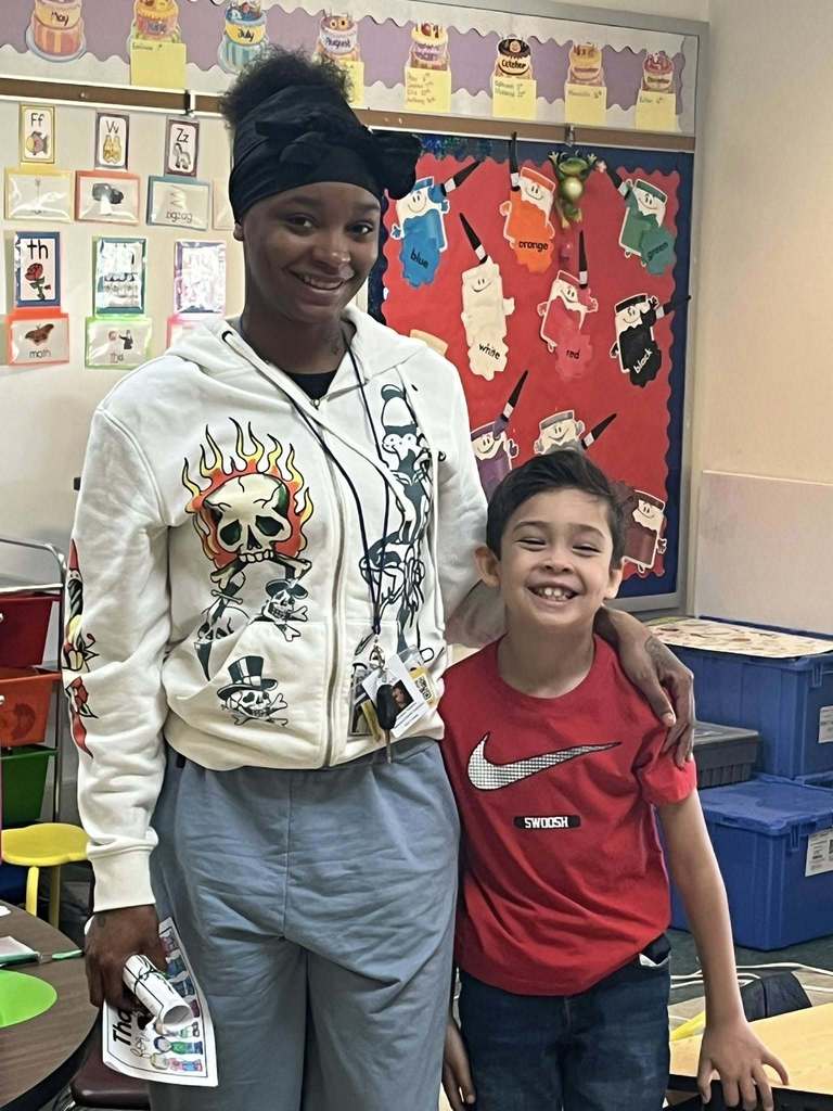 A boy is standing next to a women and they are both smiling. 