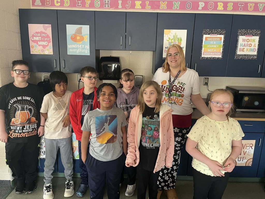 Students and adults posing in a classroom. 