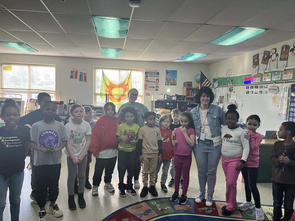 Students and adults posing in a classroom. 