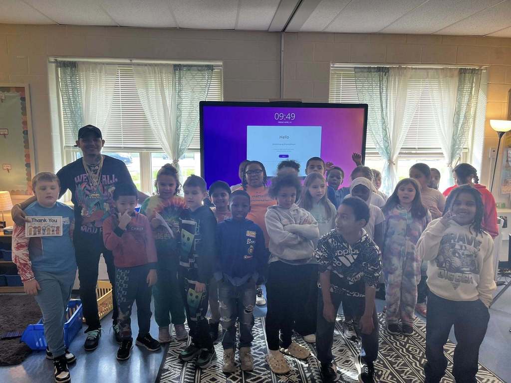 Students and adults posing in a classroom. 