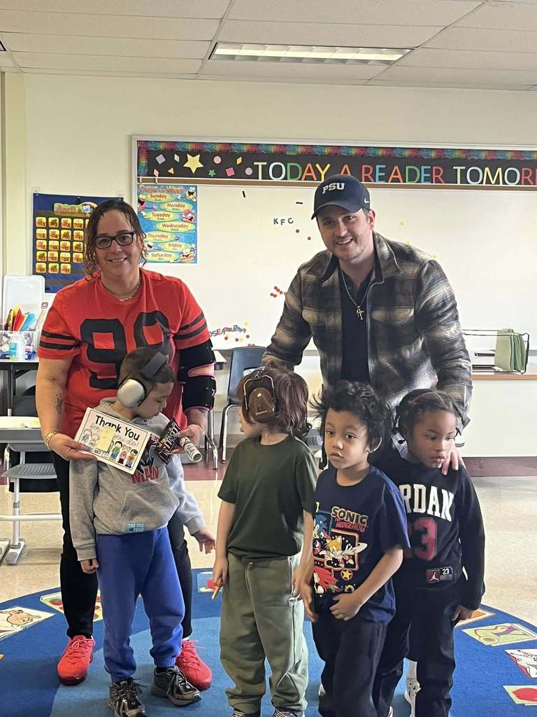 Students and adults posing in a classroom. 