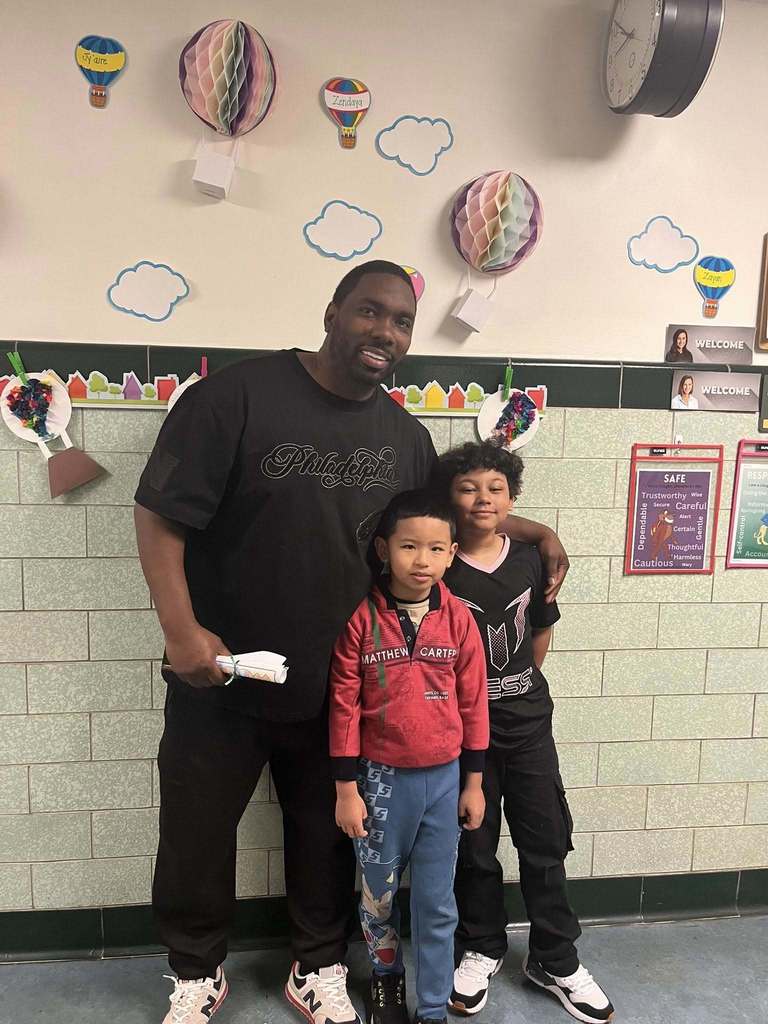 Two kids are standing next to a man and they are all smiling. 