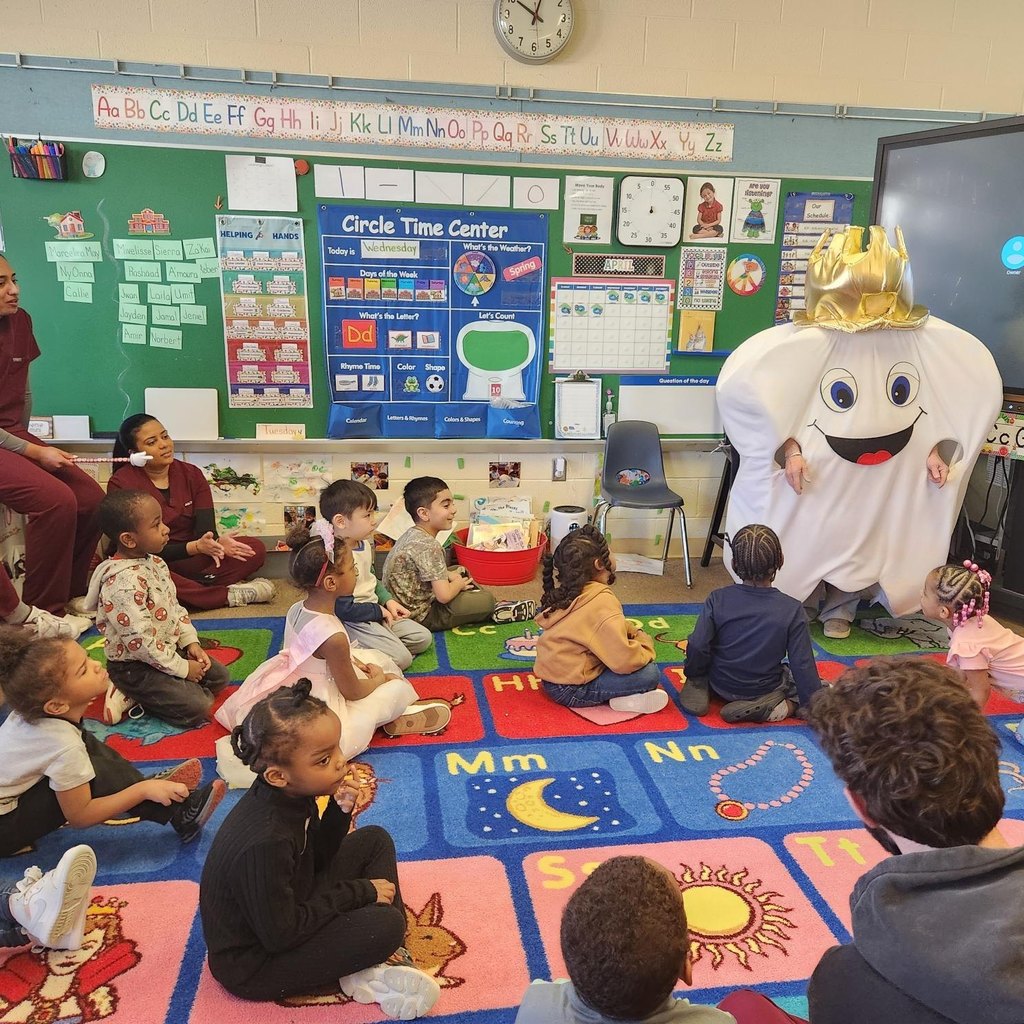 A tooth costume with a crown talking to a classroom of students. 