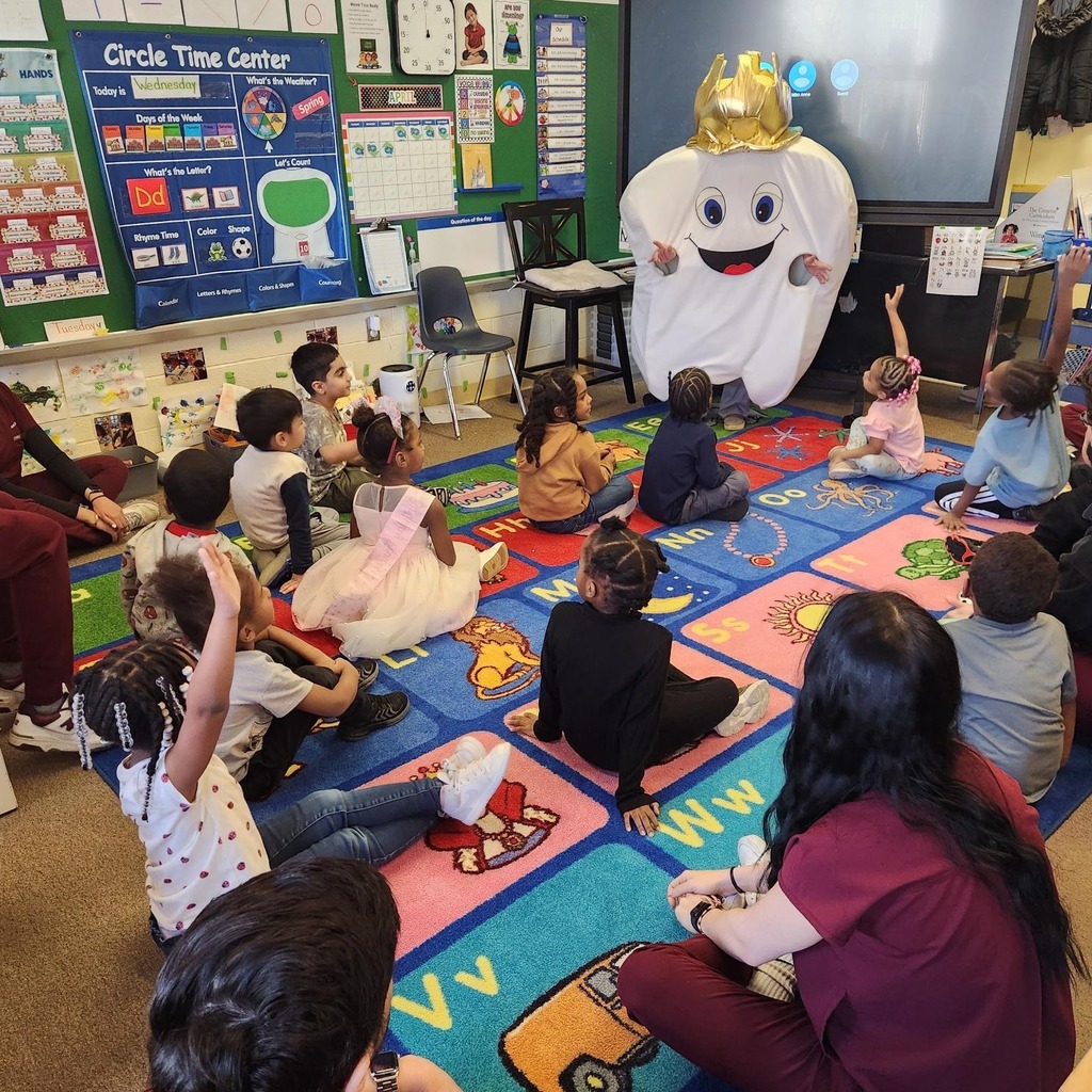 A tooth costume with a crown talking to a classroom of students. 