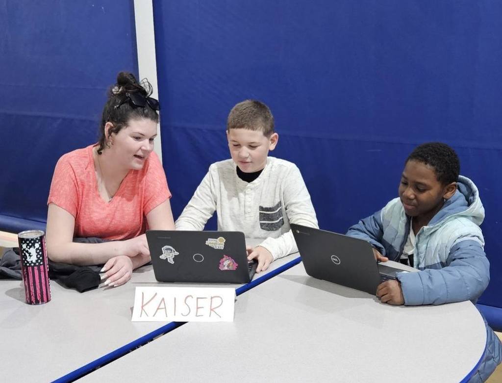 Students sitting at circle tables in school and there is a computer in front of them. 