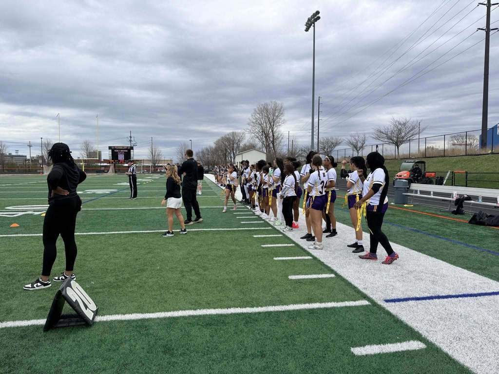 Erie High Royals Girl Flag Football Team and staff standing on the side line. 