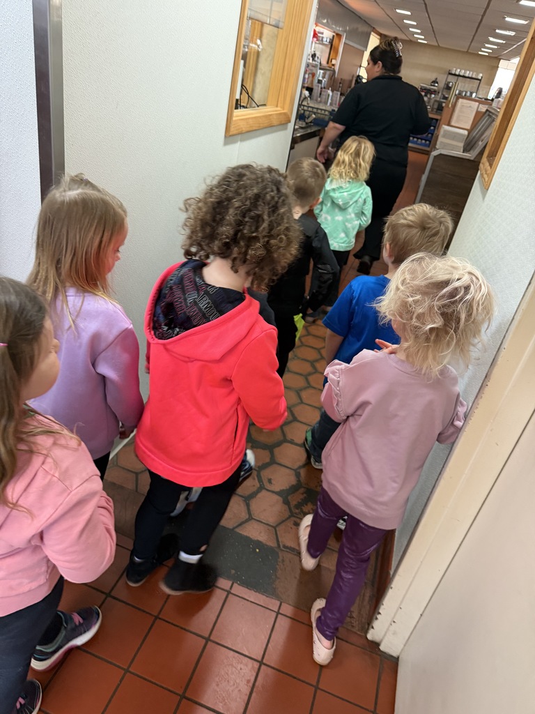 Students walk in a line touring the inside of a restaurant 