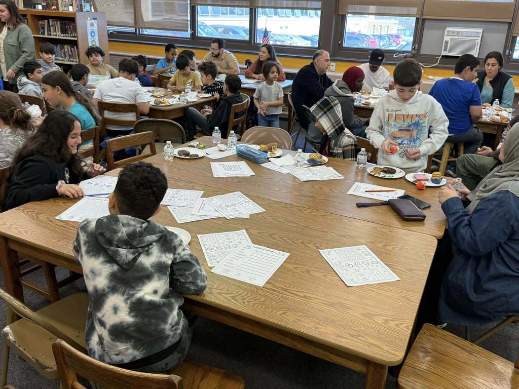 Students sitting at a table with paper and food in front of them. 