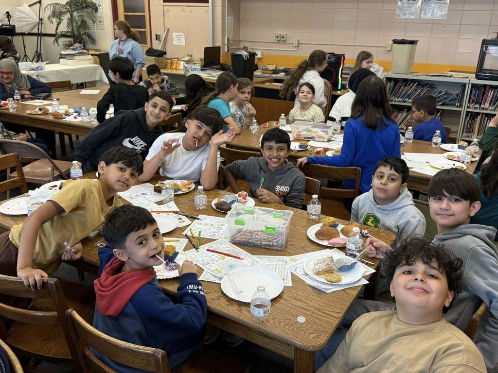 Students sitting at a table with paper and food in front of them. 