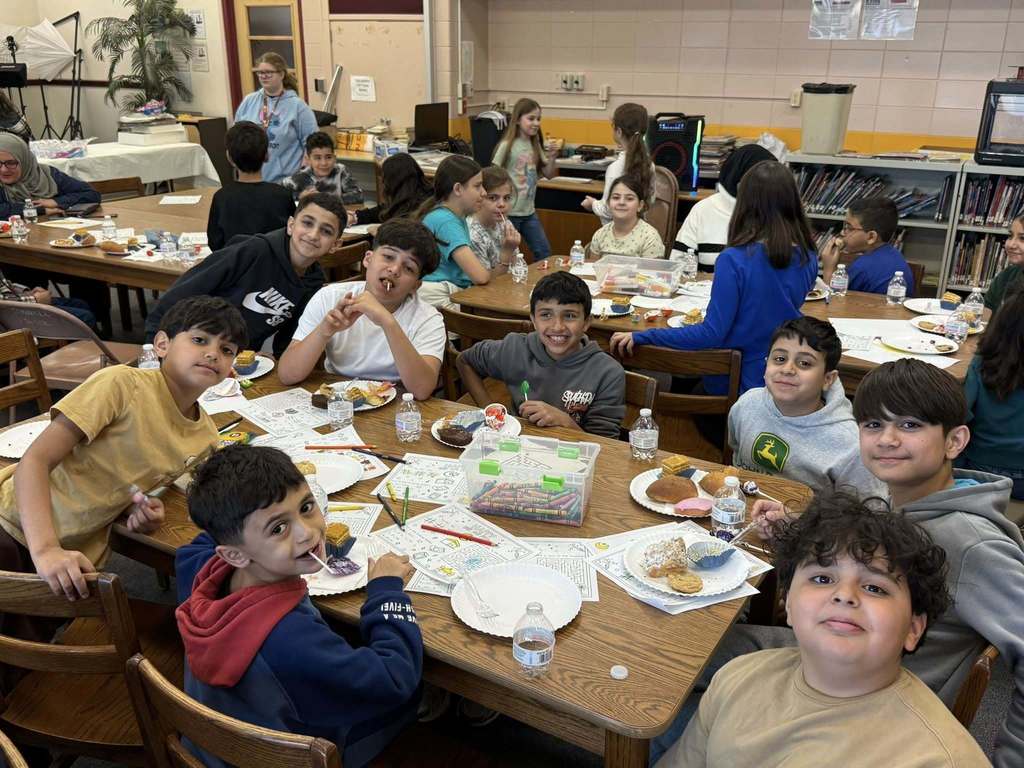 Students sitting at a table with paper and food in front of them. 
