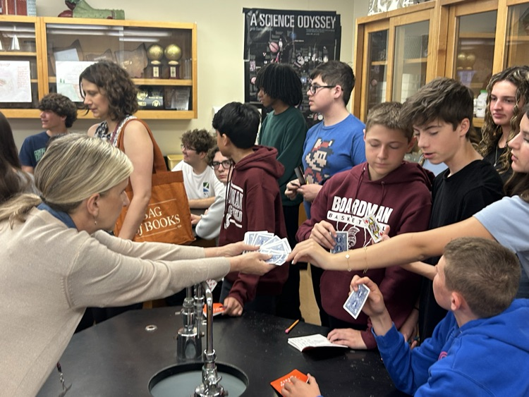 high school and 8th graders working together assembling a paper version of an eco system