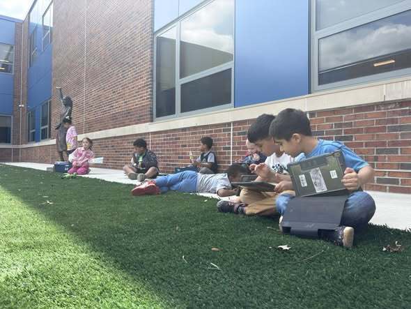 Students using their ipads and learning outside.