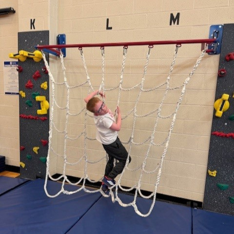 student climbing ropes ladder