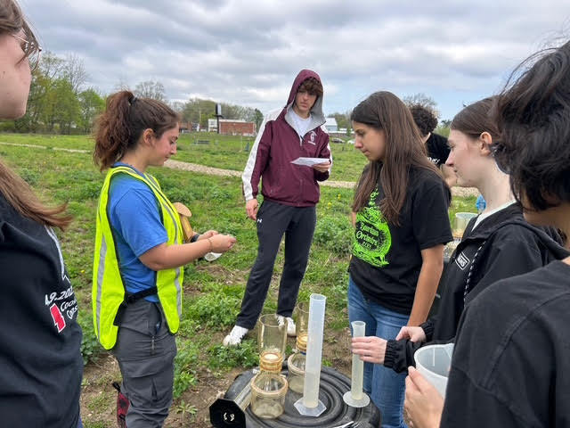students gathered around a Kent State field monitoring water quality