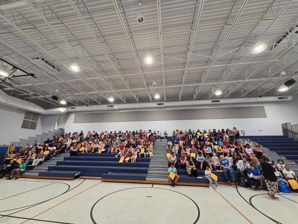 Students sitting on bleachers in their school gym. 