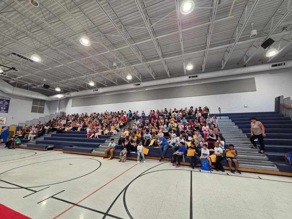 Students sitting on bleachers in their school gym. 