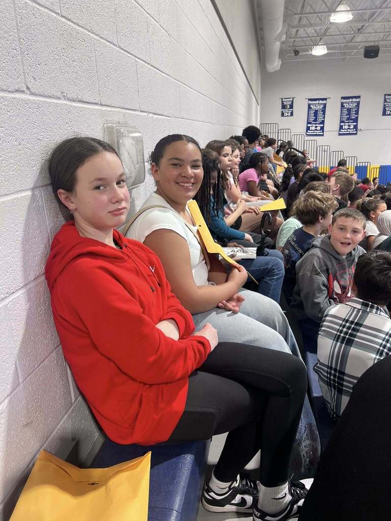 Students posing while they sit on the bleachers. 