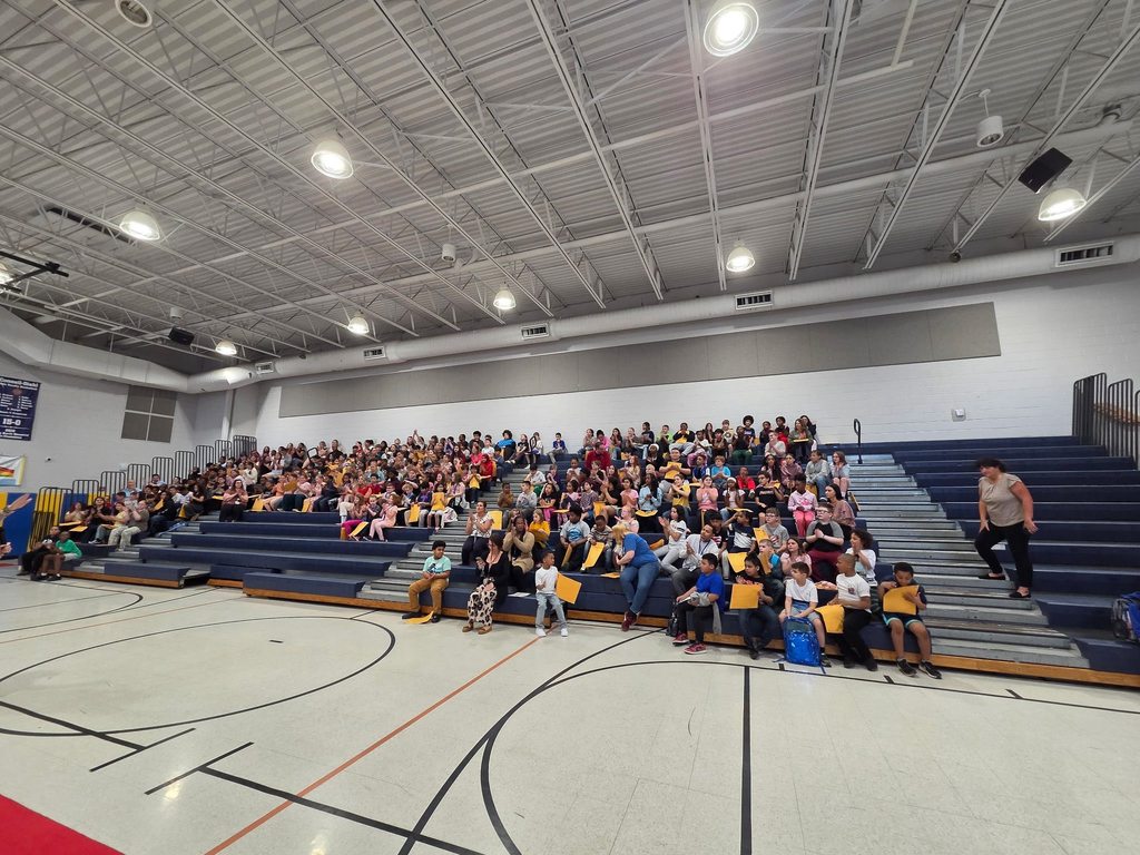 Students sitting on bleachers in their school gym. 