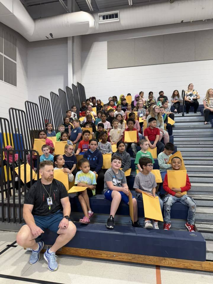 Students sitting on bleachers in their school gym. 