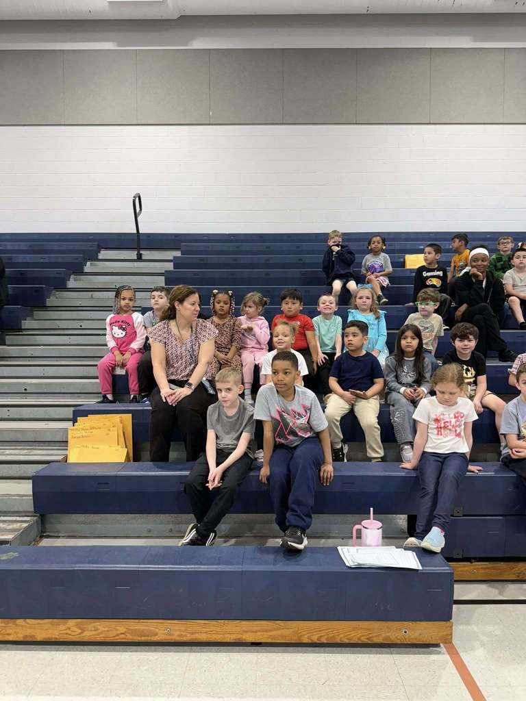 Students sitting on bleachers in their school gym. 